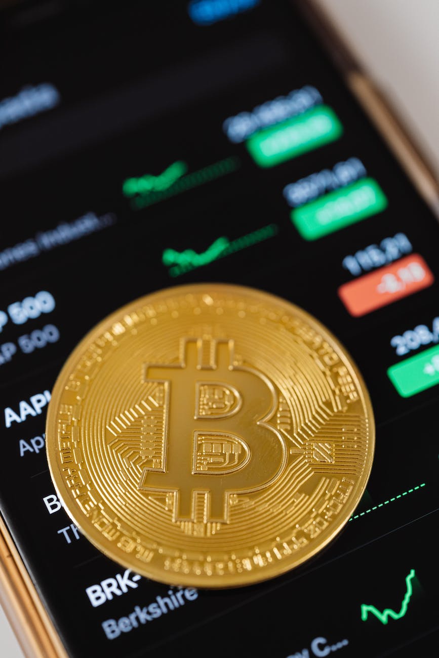gold bitcoin coin lying on a phone displaying cryptocurrency graphs